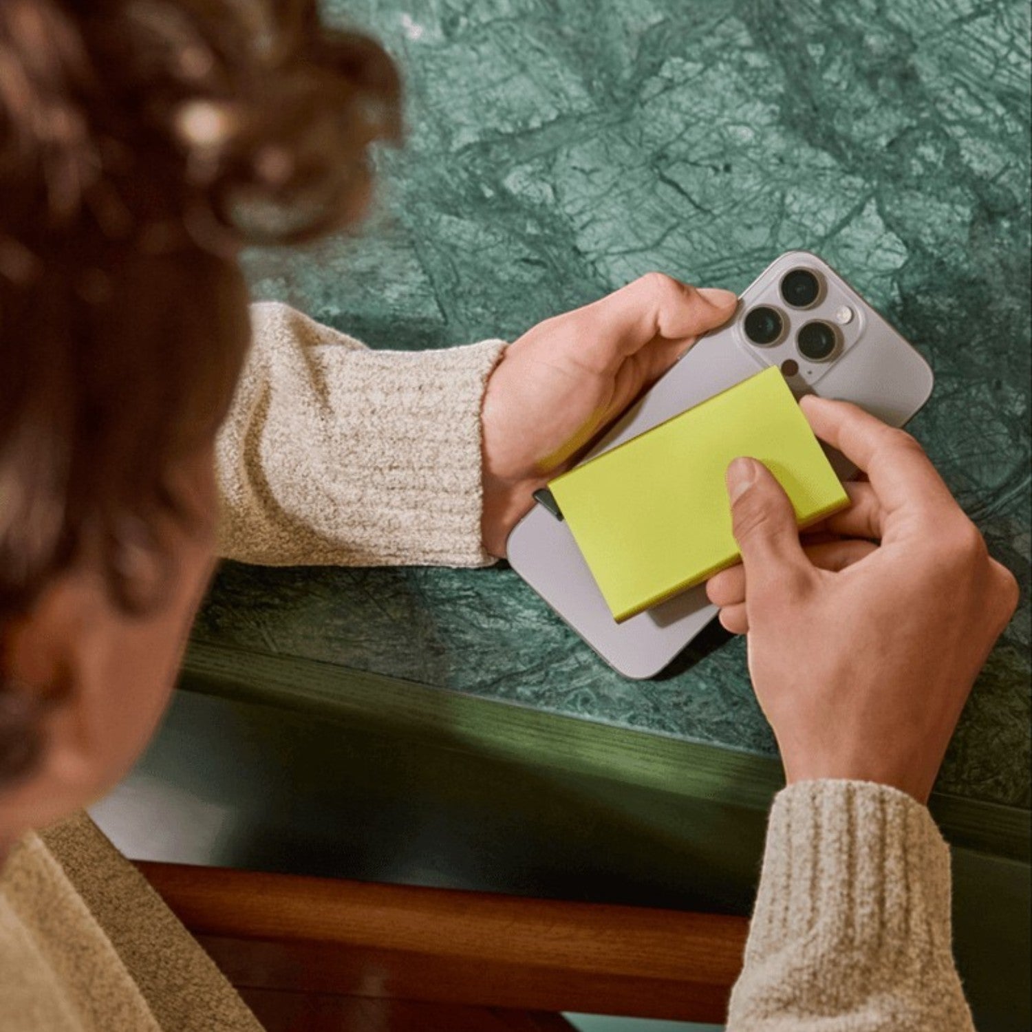 Lieblingstasche Secrid Cardprotector for MagSafe in bright yellow attached to a smartphone on a green marble table