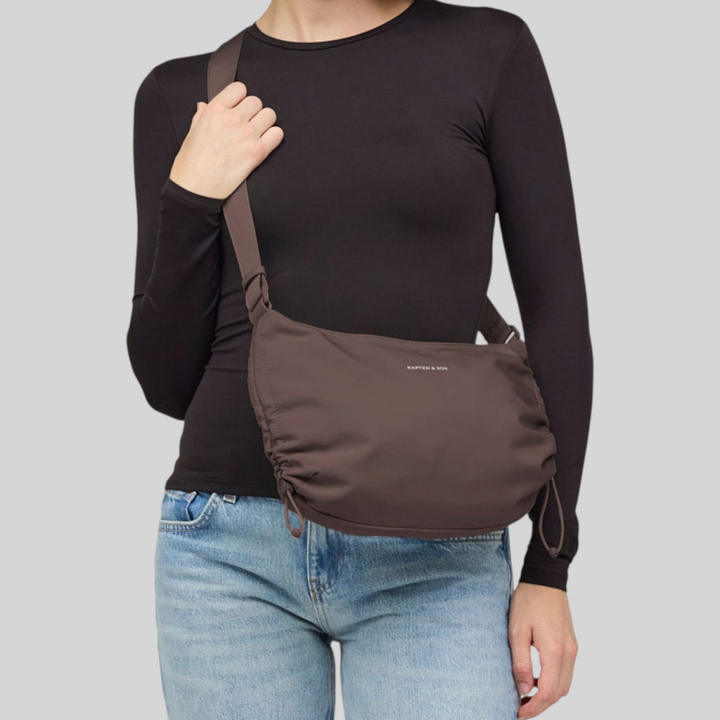 Lieblingstasche Skara Small brown crossbody bag with drawstring details worn by a woman in a black long-sleeve top