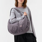 Lieblingstasche Slouchy Bag in dark grey with a relaxed silhouette, worn over the shoulder by a young woman.