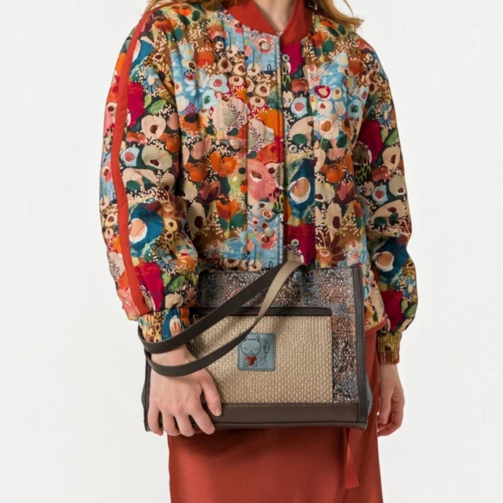 Lieblingstasche shoulder bag with textured brown fabric and a small cat logo patch held by a model in a floral jacket