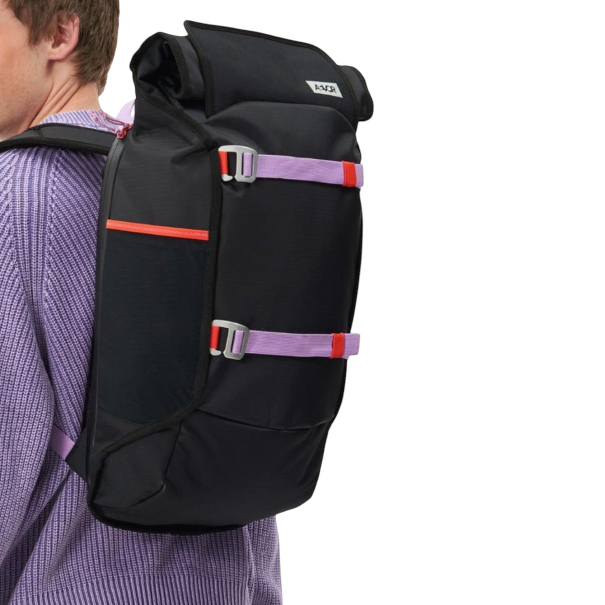Lieblingstasche Trip Pack black roll-top backpack with purple and orange straps worn by a man in a lilac sweater