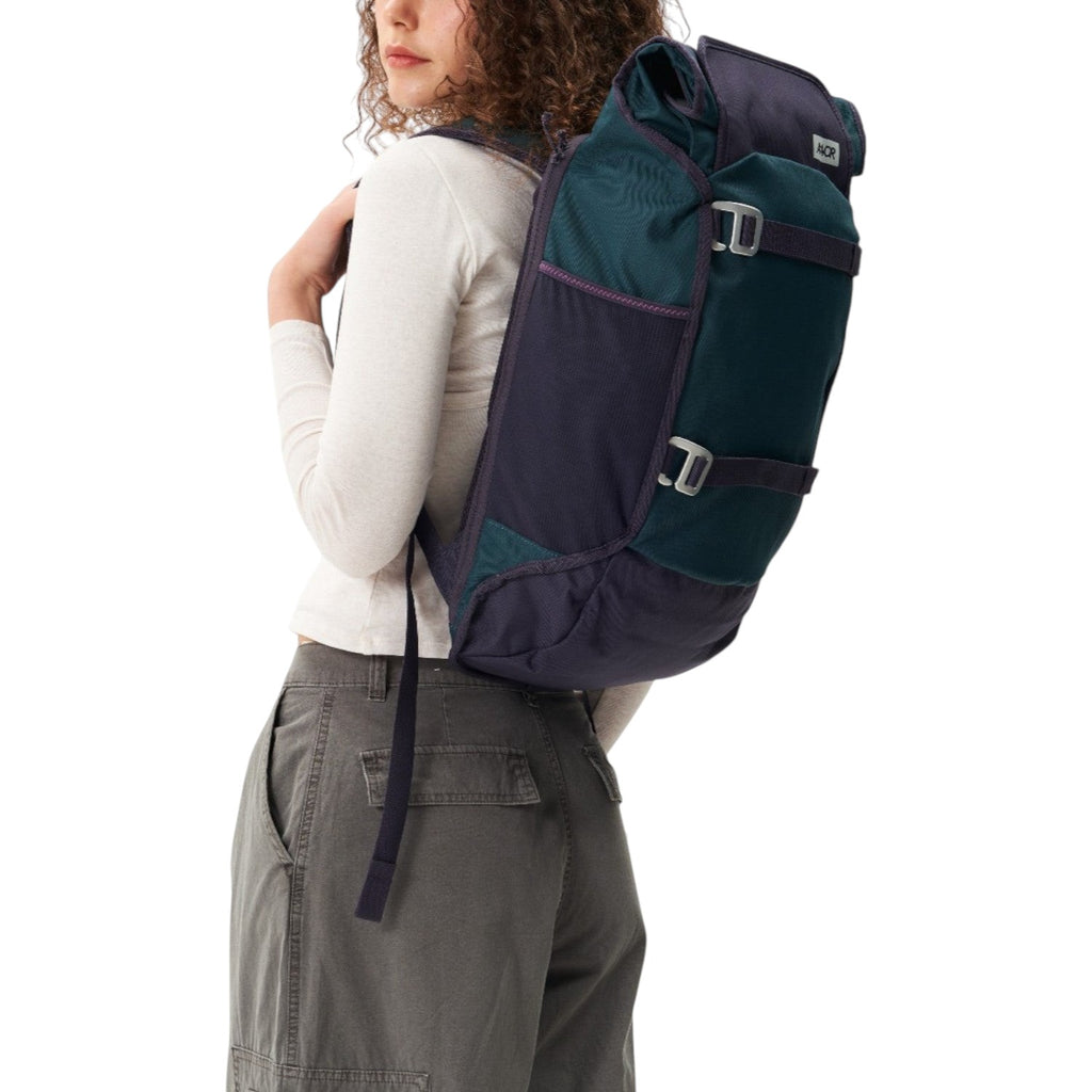 Lieblingstasche Trip Pack backpack in dark green and navy blue worn by a woman against a white background
