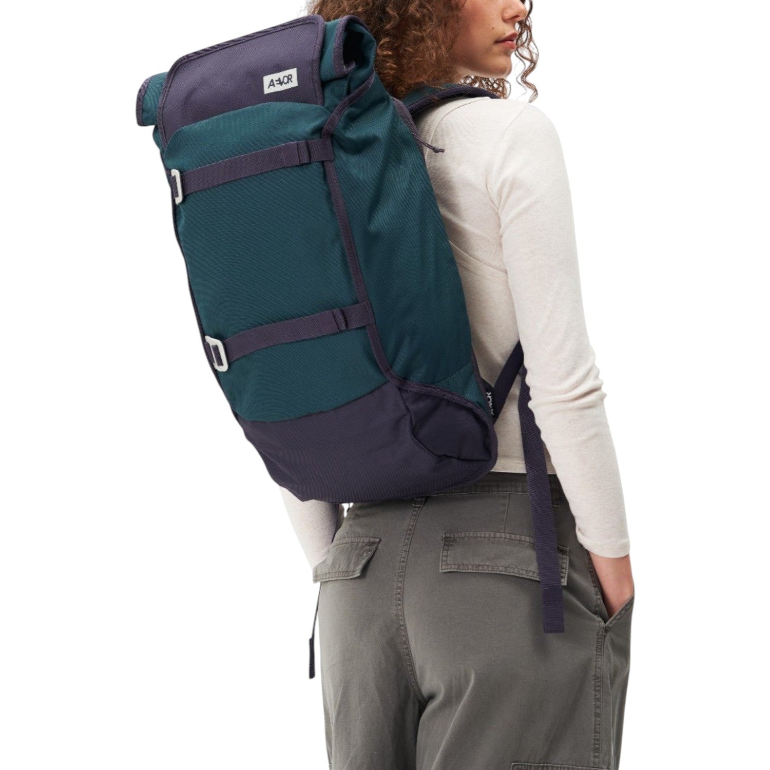 Lieblingstasche Trip Pack backpack in teal and dark purple worn by a woman against a white background