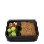 Lieblingstasche Satch black plastic lunch box with removable divider containing a sandwich, grapes, and nuts.